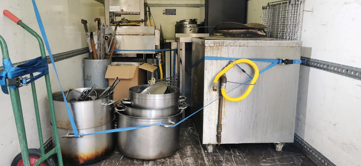 Catering equipment, large cooking pots and a trolley held with straps inside a DNE van